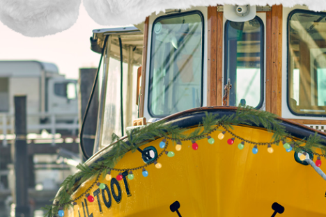 Yellow boat with holiday garland and lights, wearing a giant Santa hat.